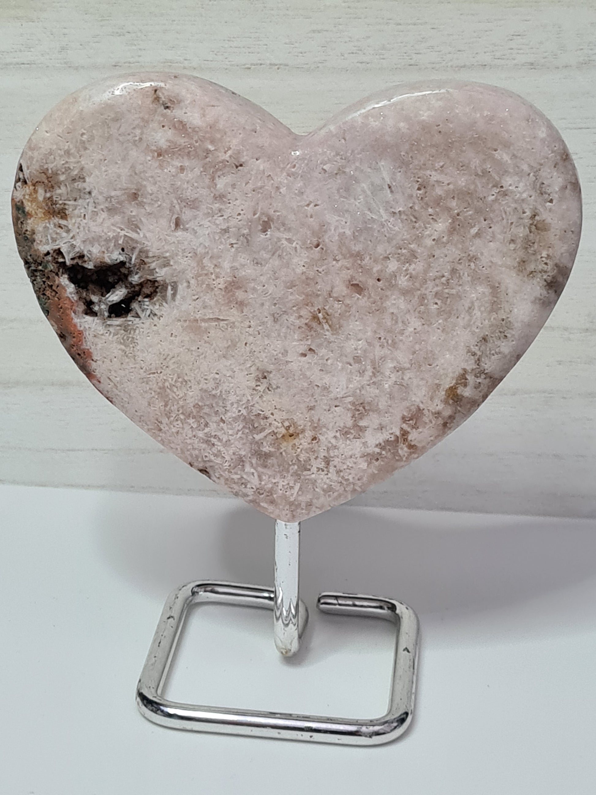 Natural Pink Amethyst Heart with needle like structure, natural caves on silver coloured stand.