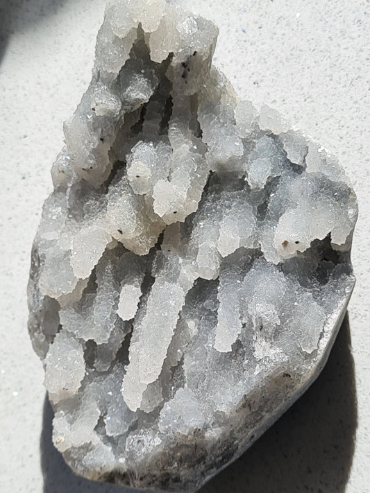 Natural Raw Grey Chalcedony Stalactite formation from India with clear quartz mirco druzy.
Photographed on a white granite background.