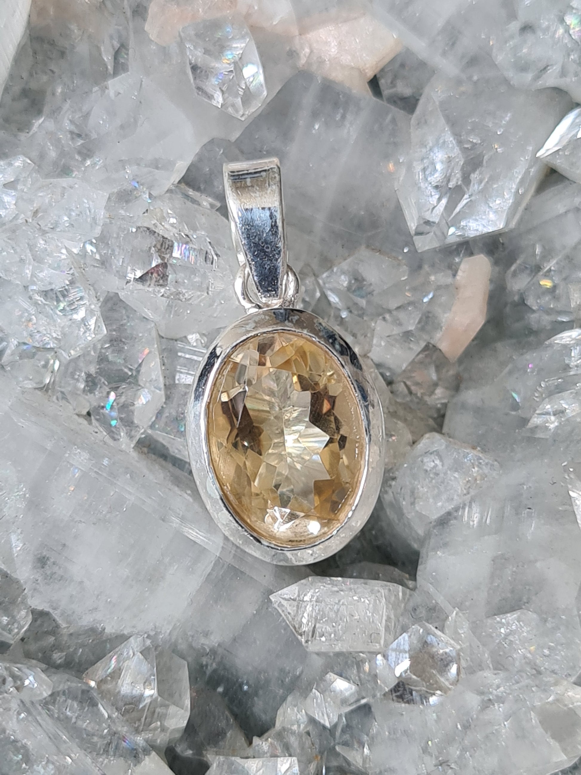An oval faceted natural citrine pendant set in sterling silver.
Photographed on an apophyllite cluster background. 