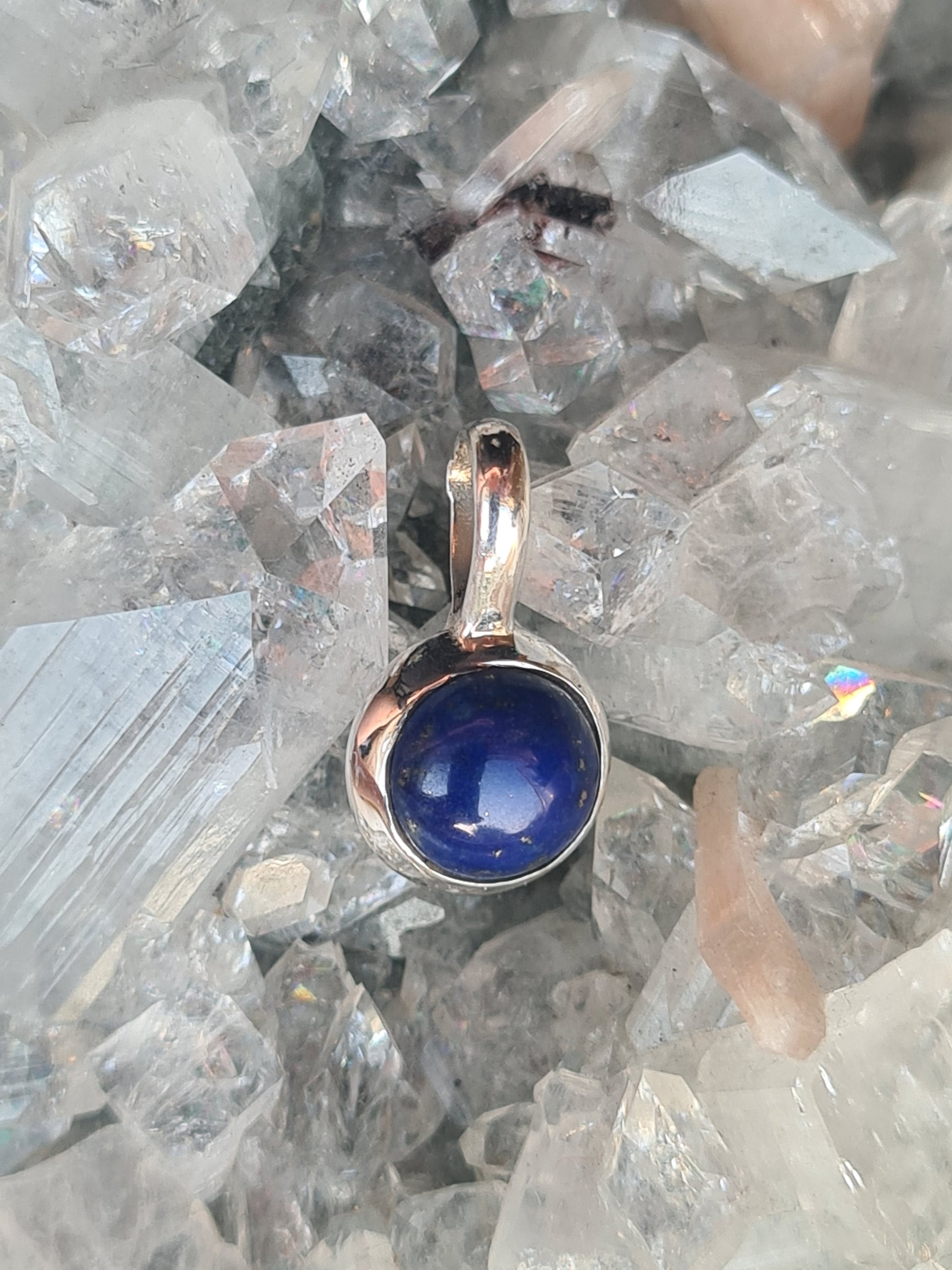 A sterling silver pendant rubover set with a lapis lazuli cabochon, measuring 8mm diameter.