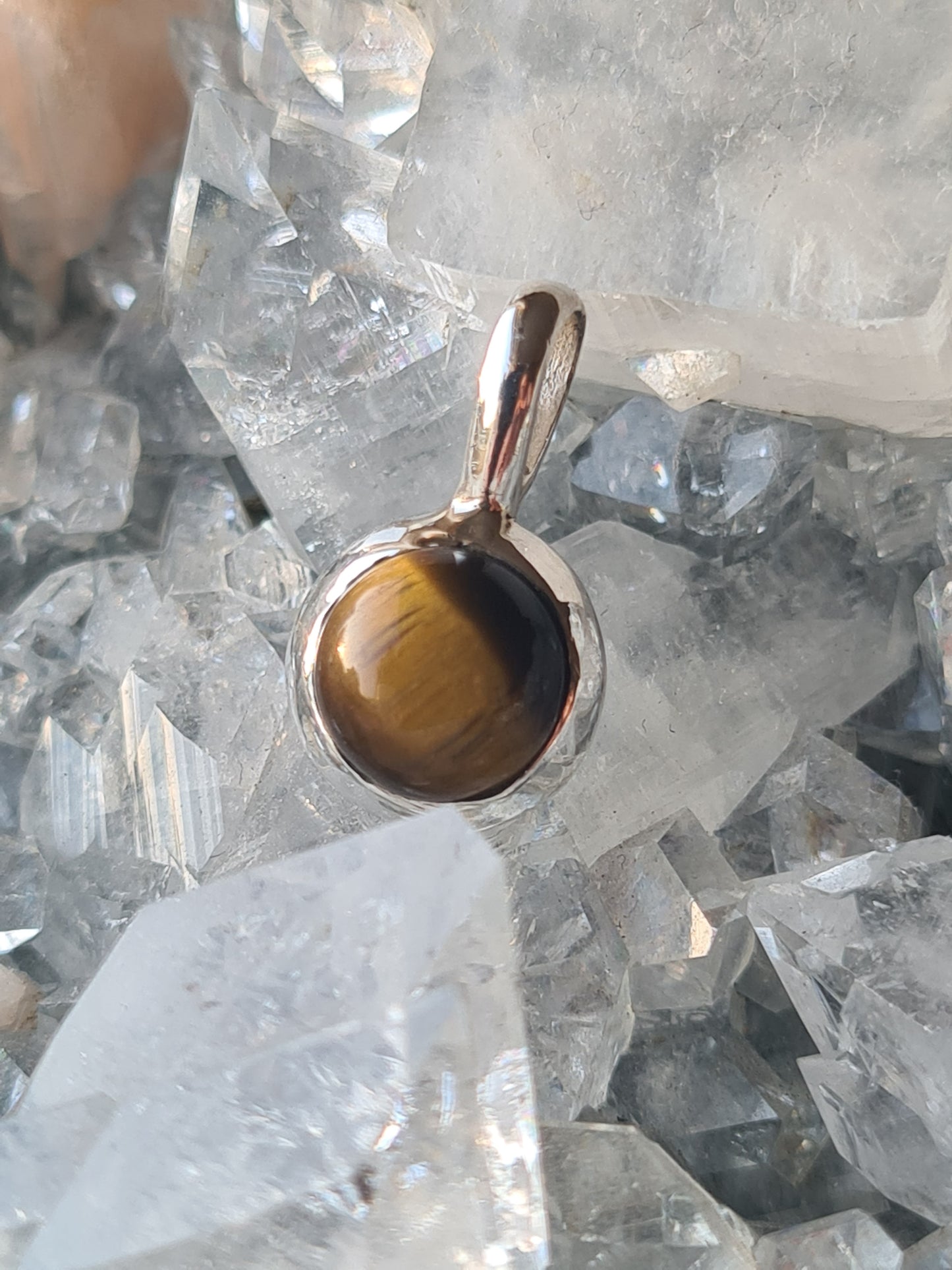 A simple single stone round cabochon tigers eye pendant in sterling silver