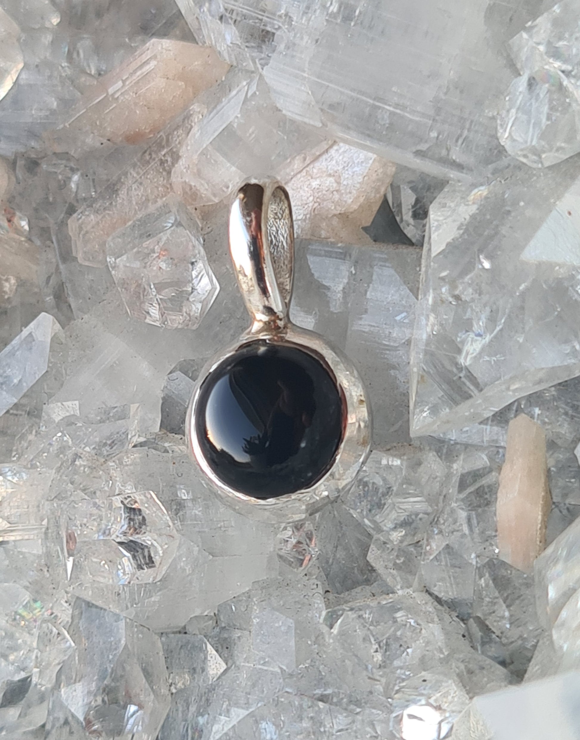 A sterling silver pendant rubover set with a round black onyx cabochon