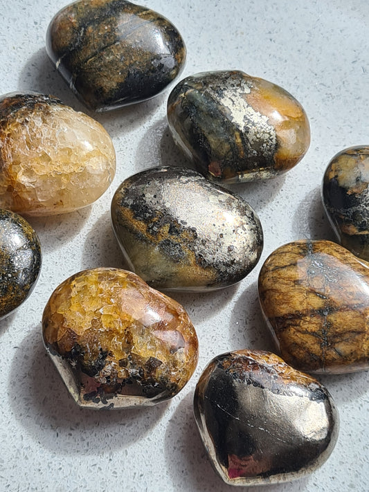 Pyrite (gold) and Golden Healer (yellow) crystal hearts, measuring approx 3.5cm wide, photographed as a group on a white background. 