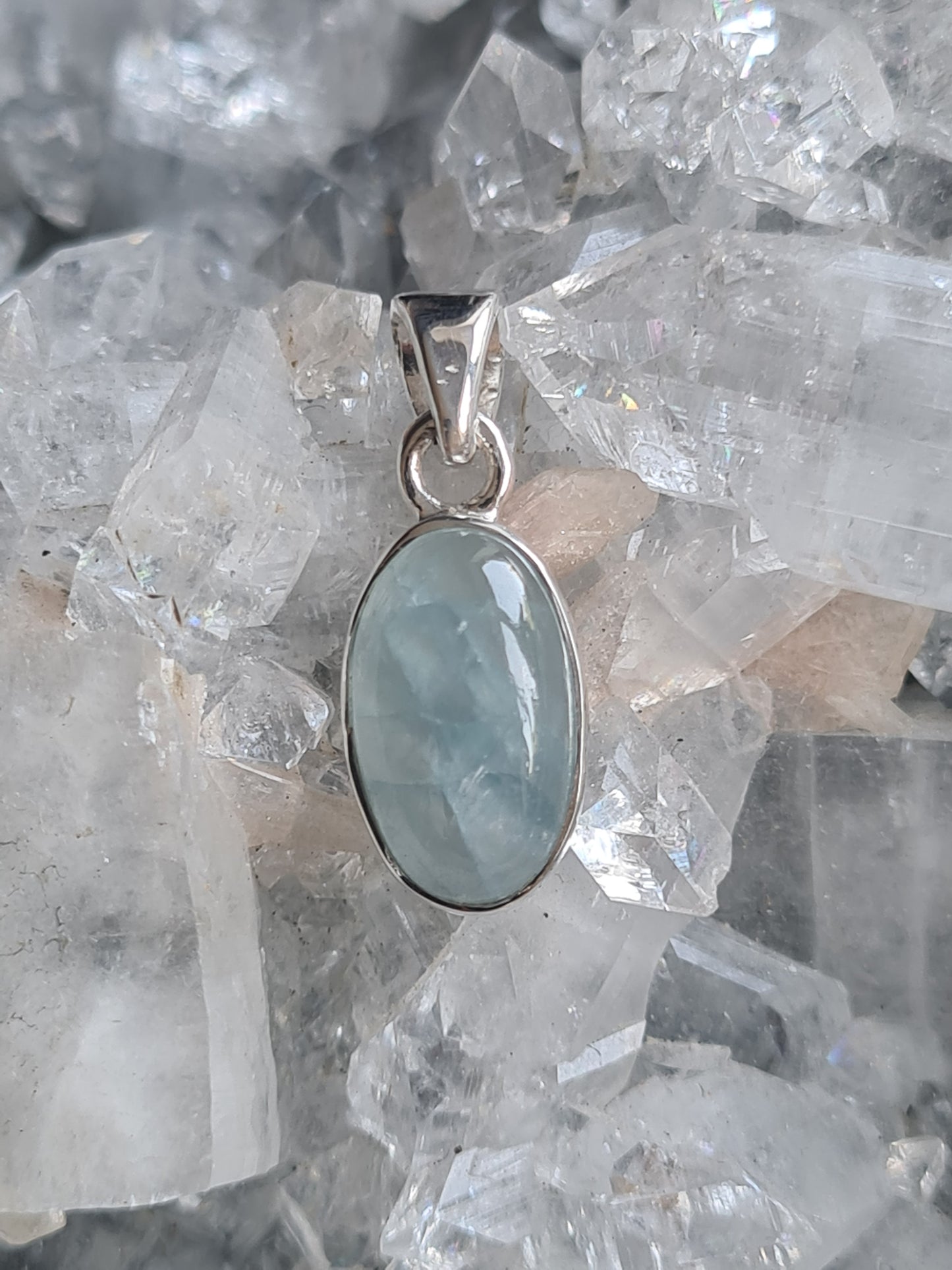 An oval cabochon aquamarine single stone pendant, rubover set into sterling silver.