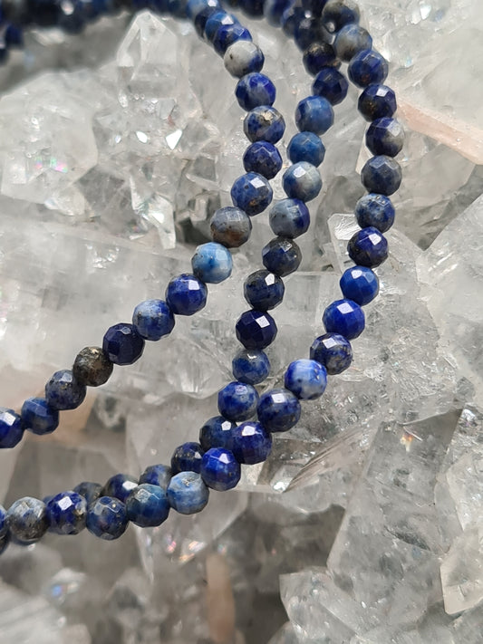 Faceted lapis lazuli beaded bracelet 3mm size on elastic. Blue colour. Photographed on an apophyllite cluster. 
