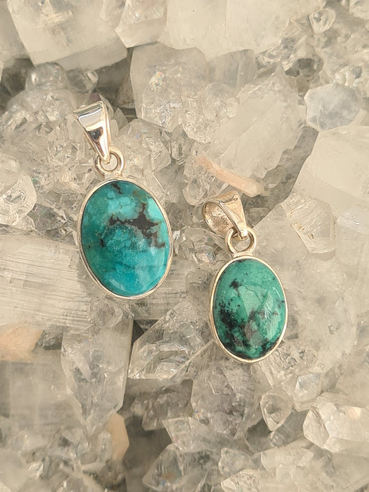Two oval Turquoise set pendants on sterling silver. Vivid blue/green colour turquoises with natural black veining.
Photographed on a natural apophyllite cluster background. 