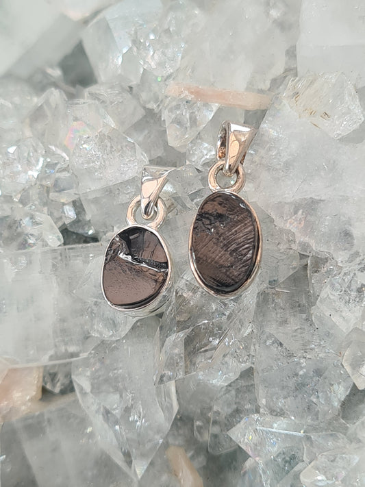 Two mini shungite pendants in sterling silver. Both oval shaped with a raw edged black Russian shingite.