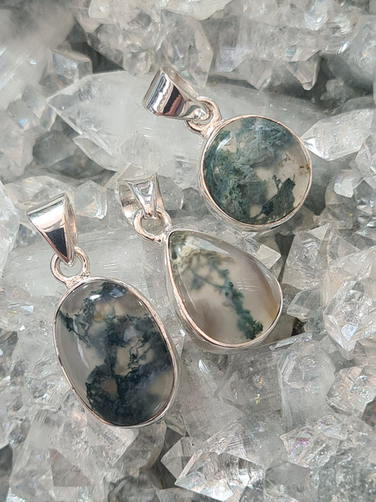 Collection of Moss Agate Set Pendants in Sterling Silver. One available as pear shape, round shape and oval shape. On crystallised background.