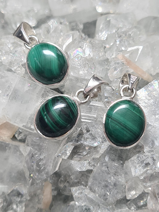 Three malachite set pendants in sterling silver. Each oval shaped with natural unique green banding.