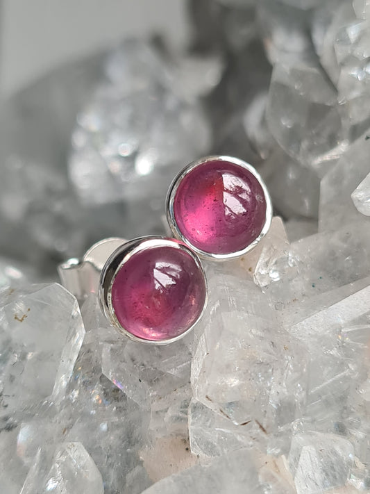 A pair of natural red ruby set stud earrings. Round cabochon ruby, rubover set in Sterling Silver. 
Photographed on a natural apophyllite cluster. 