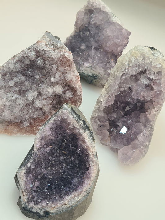 Collection of Brazilian Amethyst Cluster Freeforms, showing 4 different clusters in purple, lilac, and pink crystals.
Photographed on a white background. 