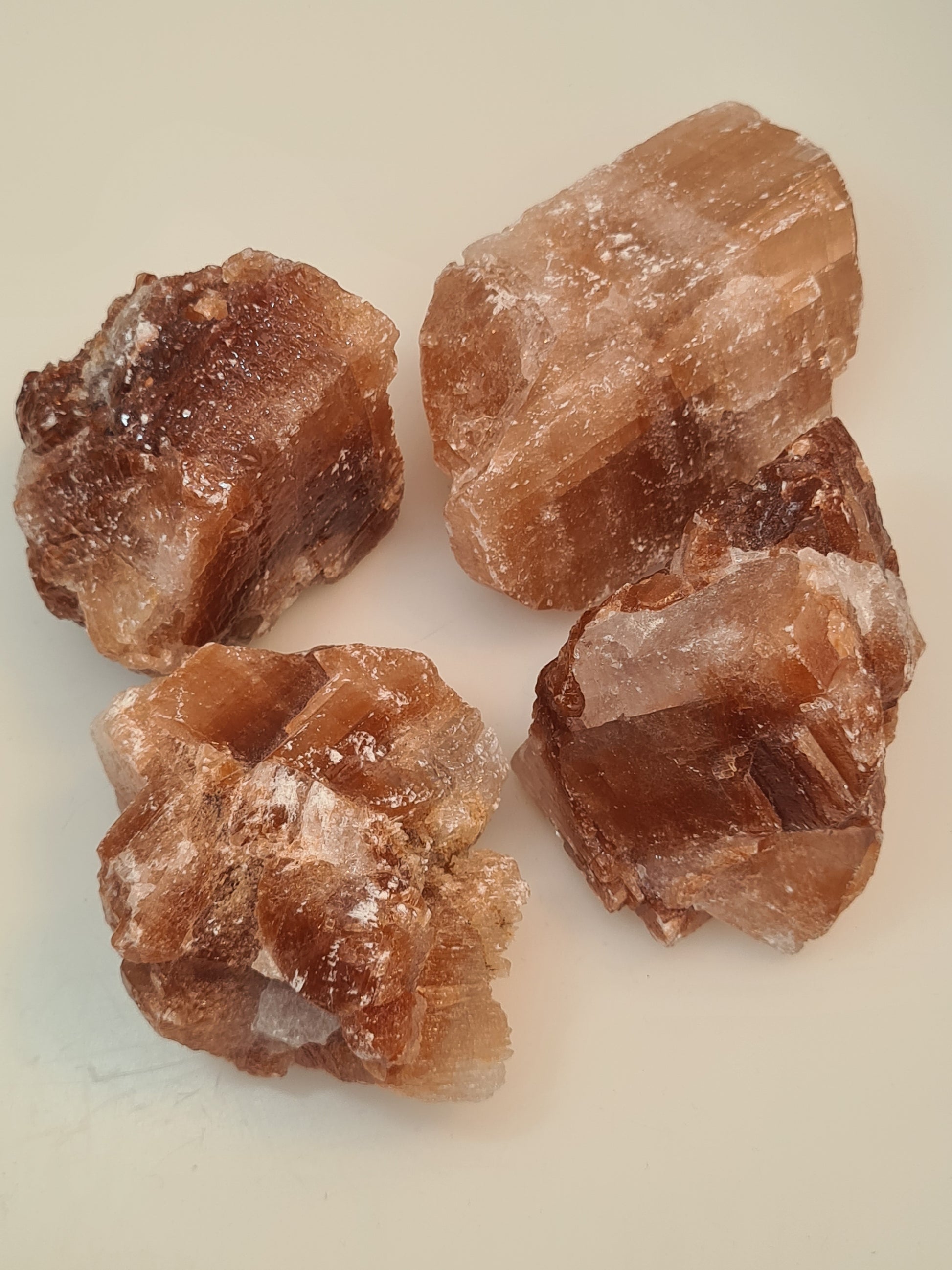 Natural Raw Red Calcite Chunks with white/orange banding. Photographed on a white background. 