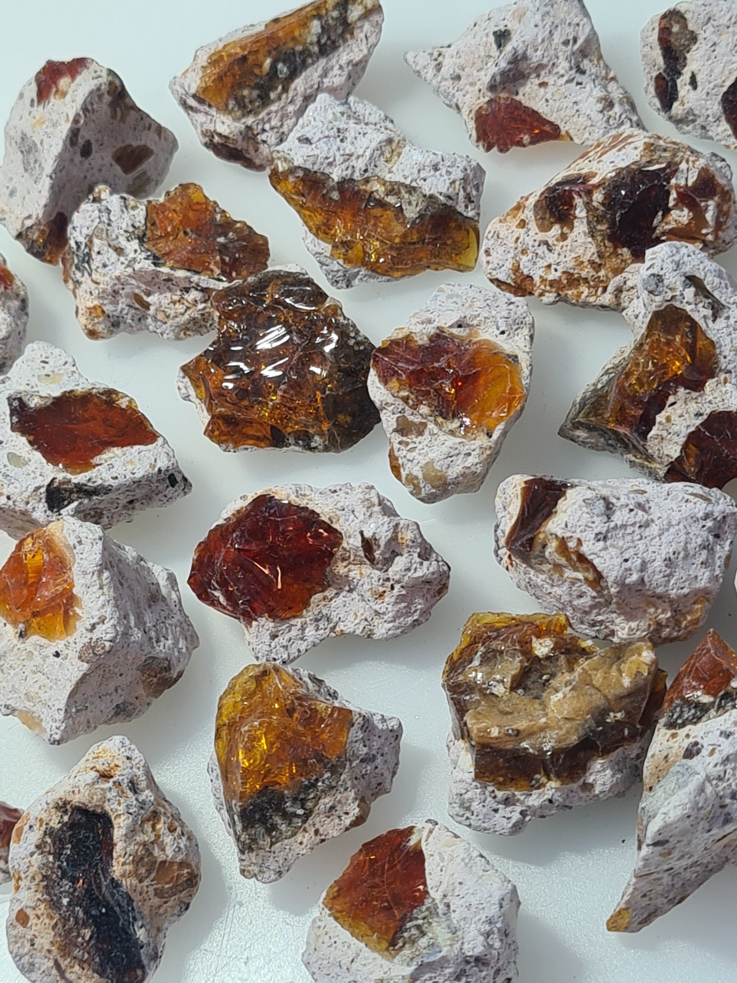 Natural fire opal from Mexico, raw form, in colours of yellow, orange and red in matrix. Photographed on a white background. 