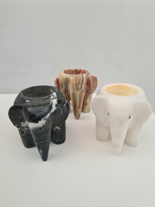 Natural stone/crystal Elephant tealight candle holders. In black marble, banded clacite or white onyx. Photographed in a group of 3 on white background. 