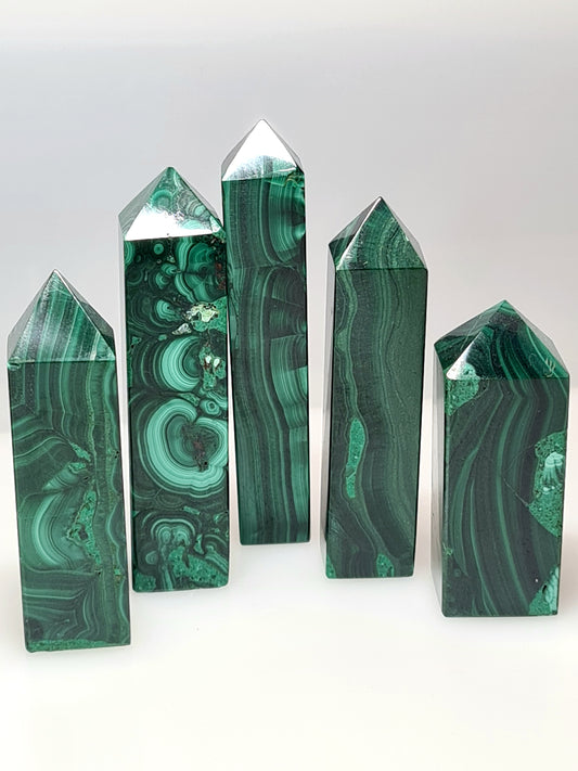 Five natural Malachite Obelisk Towers showing botroydial banding in shades of green. Photographed on a white background. 