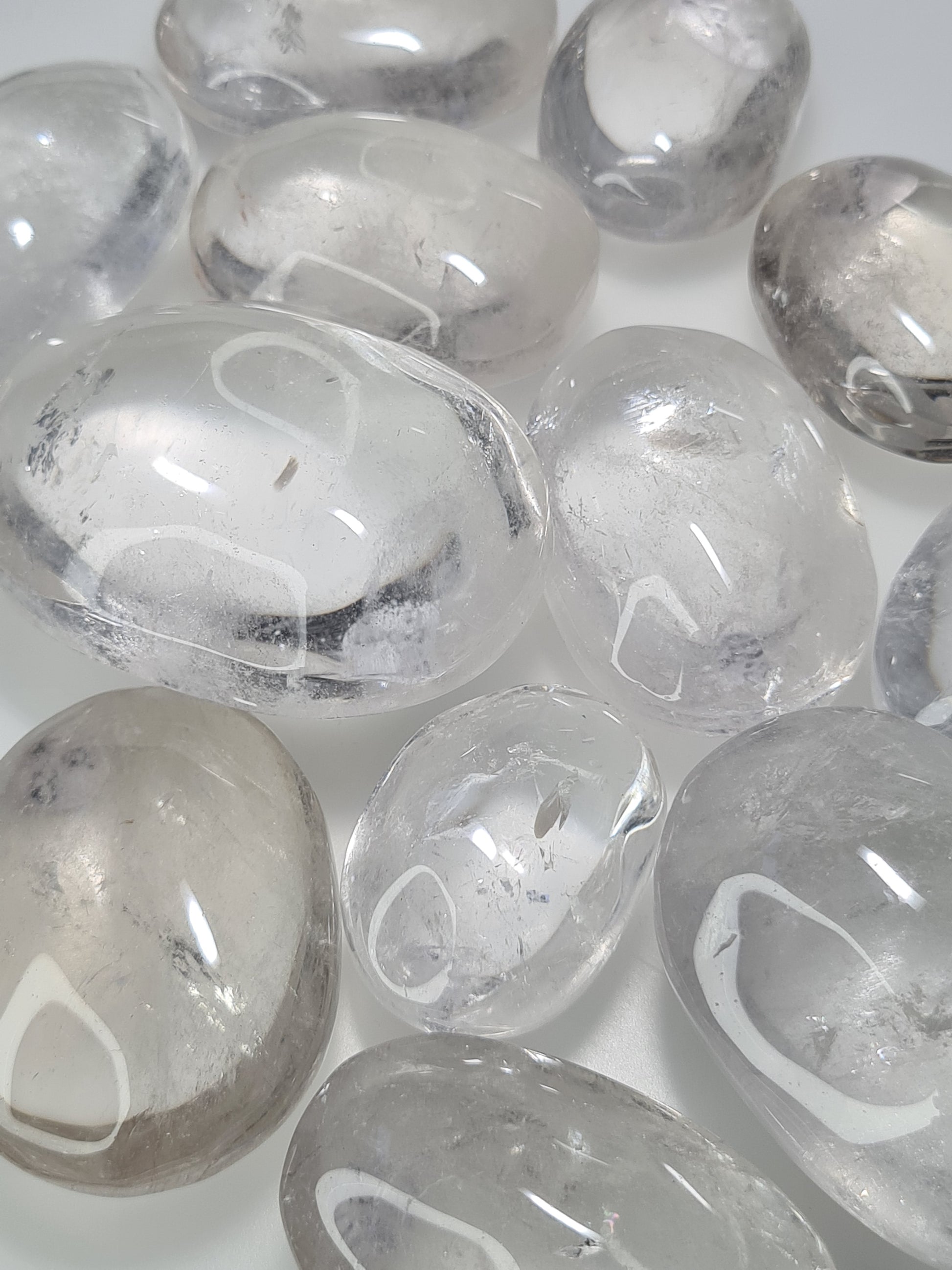 Clear Quartz Palmstones, various sizes, good clarity with natural inclusions. Photographed on a white background. 