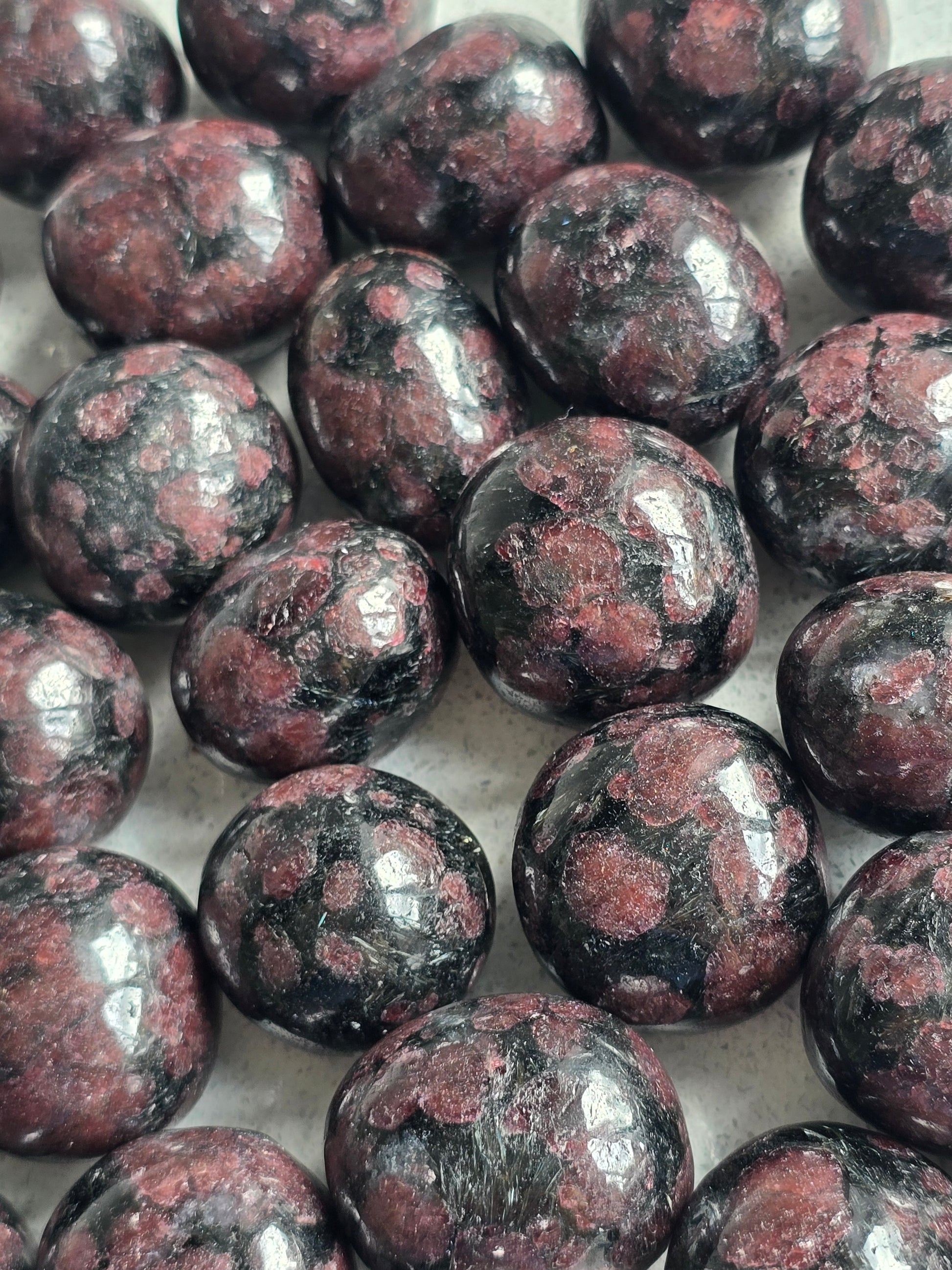 Natural Arfvedsonite and Garnet Crystal Tumblestones with black body colour and red Garnet inclusions.