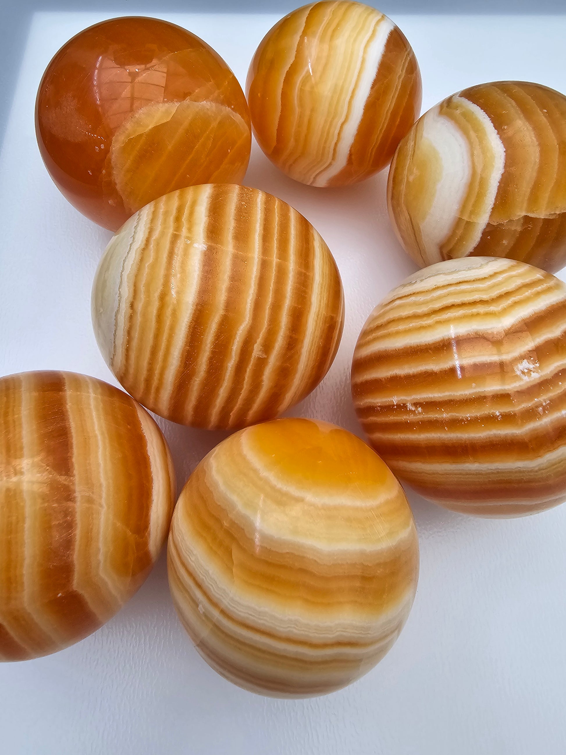 Juicy orange calcite spheres, with orange and white banding. Close up photo on a white background. 