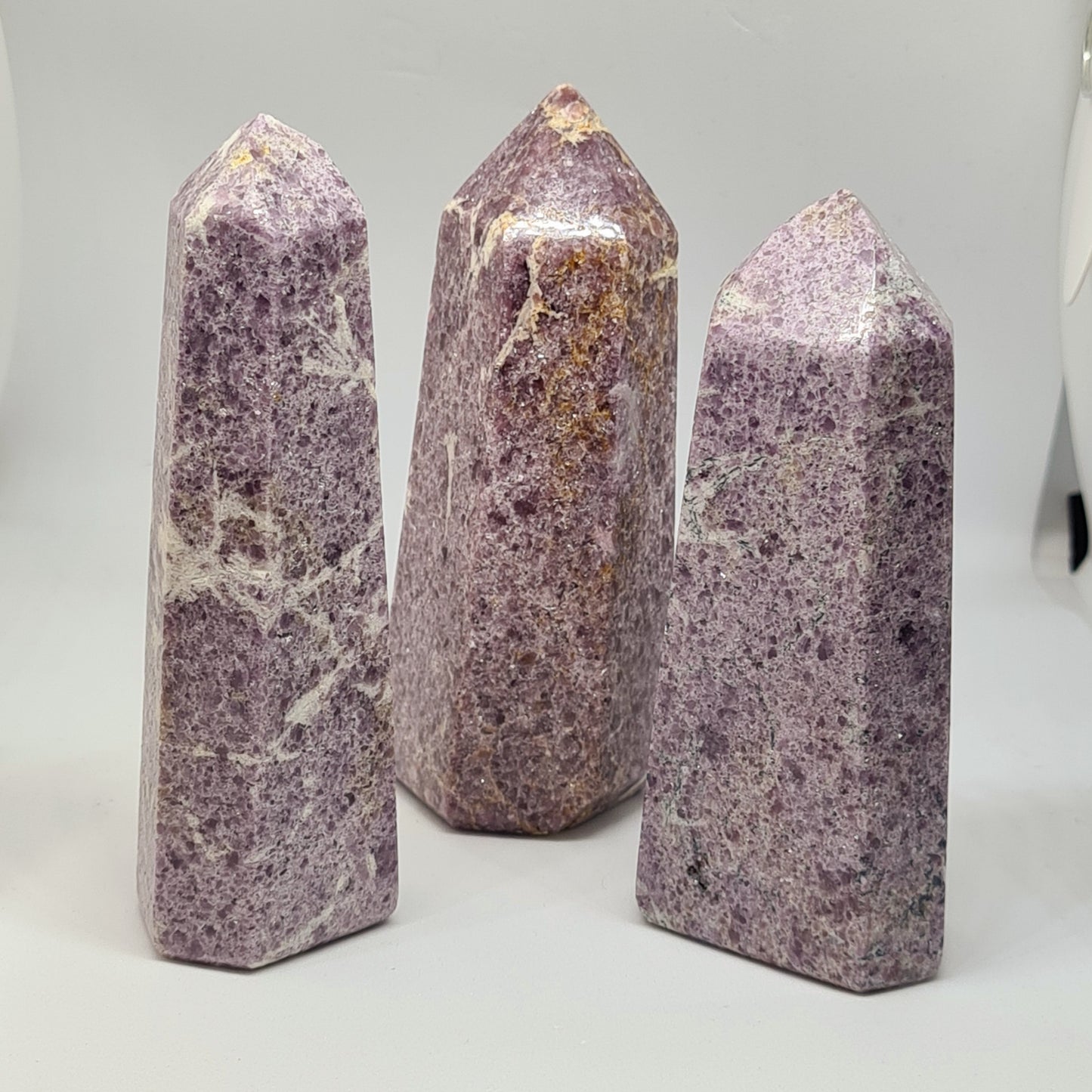 Three glittering lilac lepidolite / purple mica towers on White background
