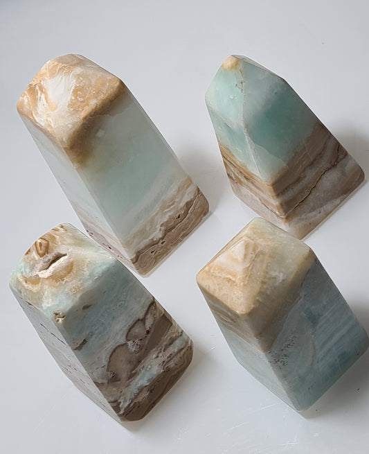 A collection of four chunky flat based Caribbean Calcite Obelisks with sea blue Calcite and white/brown Aragonite banding