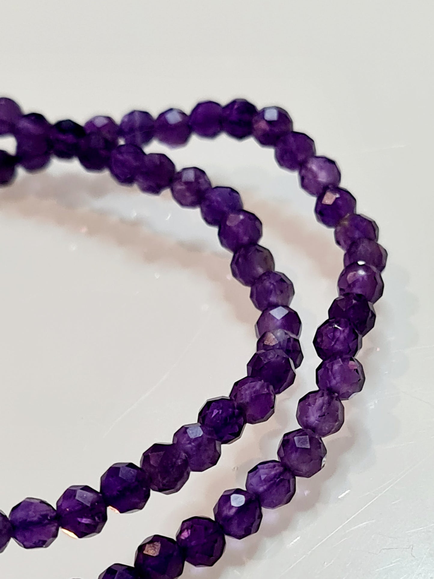 Two 4mm faceted dark amethyst bead bracelet, elasticated, on white background