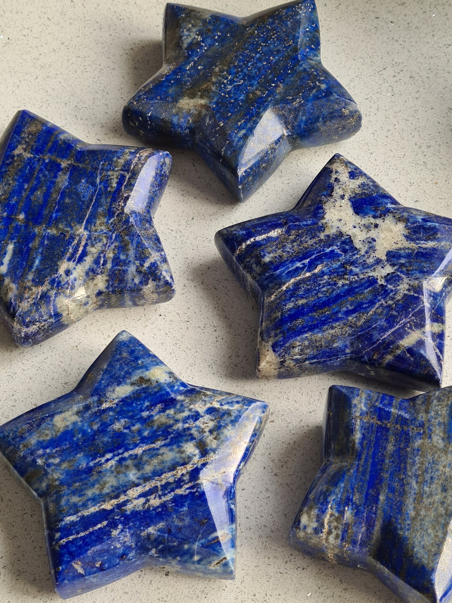 A group of vivid blue Lapis Lazuli Star carvings, with white calcite and pyrite inclusions