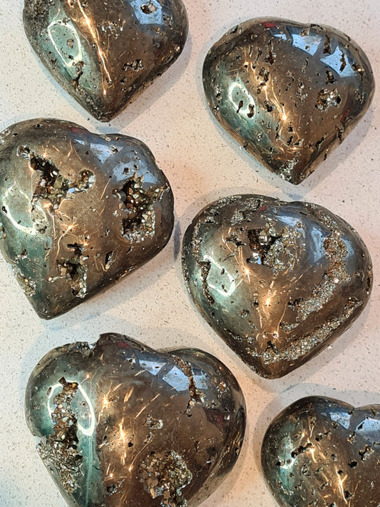 A collection of pyrite polished hearts with druzy pockets and natural features from Peru.