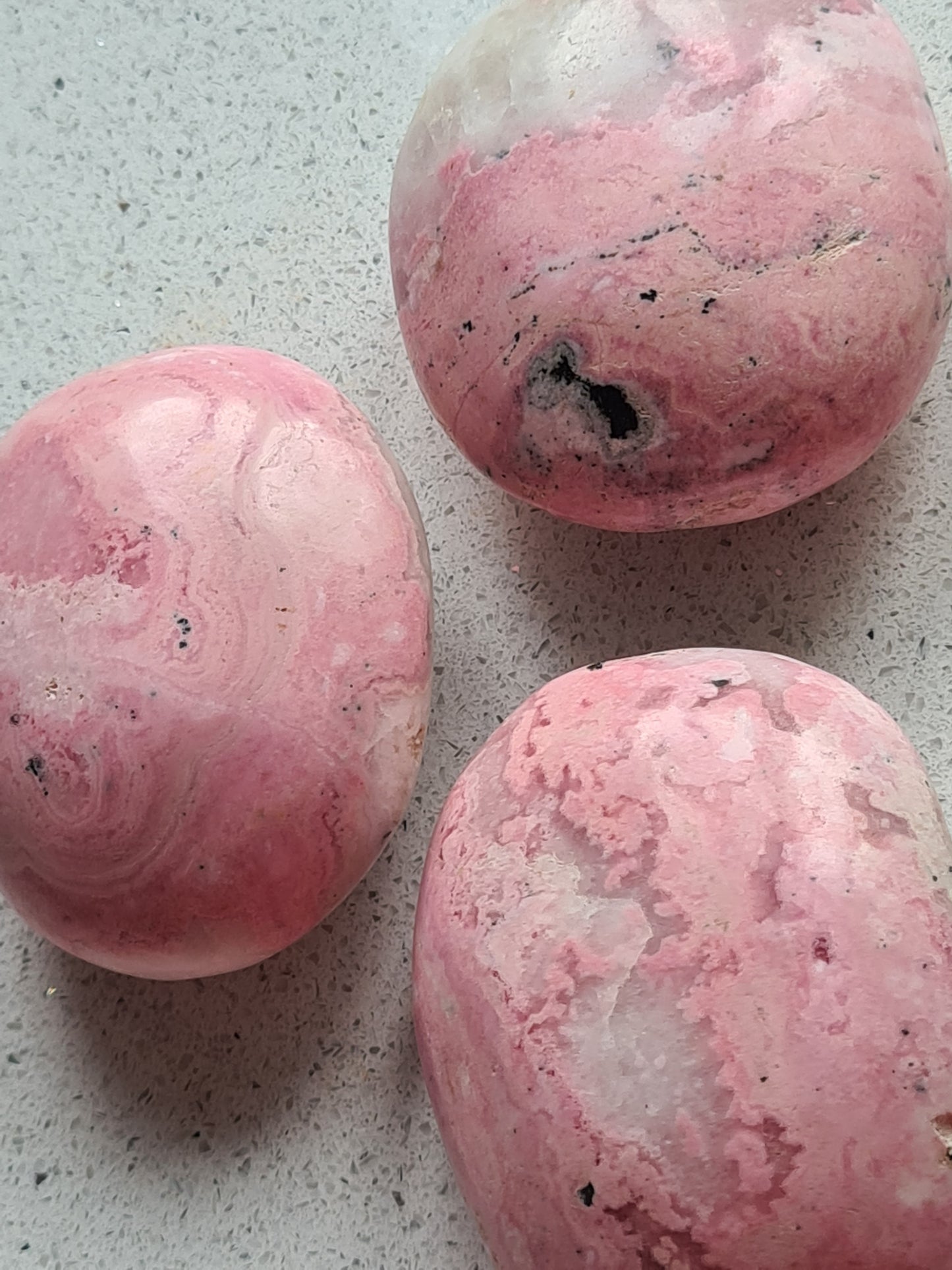 Close Up Photo of Three Peruvian Rhodonite Palmstones showing all the Pink Patterned Surface