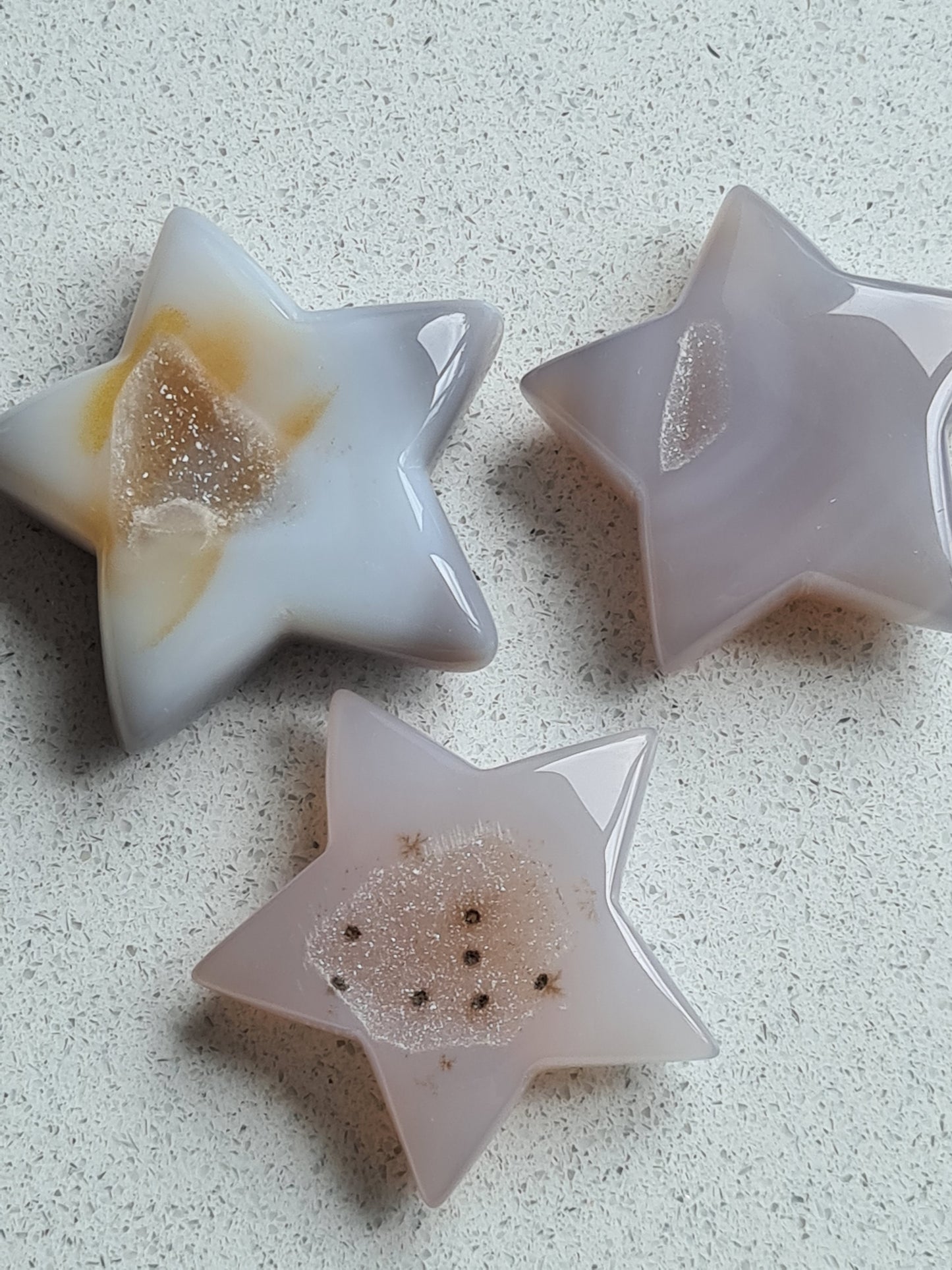 Three druzy agate stars in grey tones with clear quartz druzy on a white background