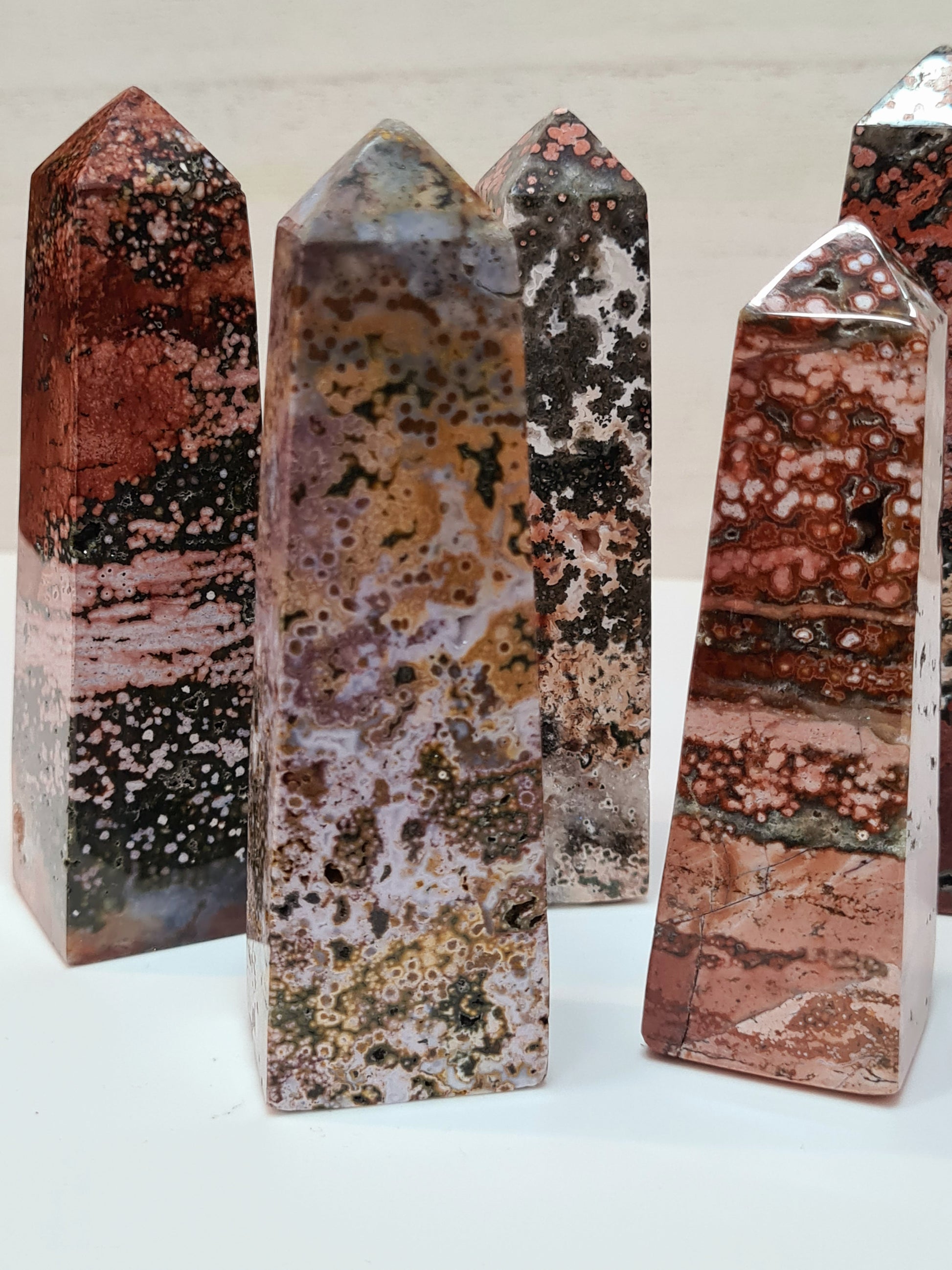 A collection of orbicular jasper obelisks with bulls-eye and spotted patterns. In colours of red, pink, purple, yellow and/or greens.