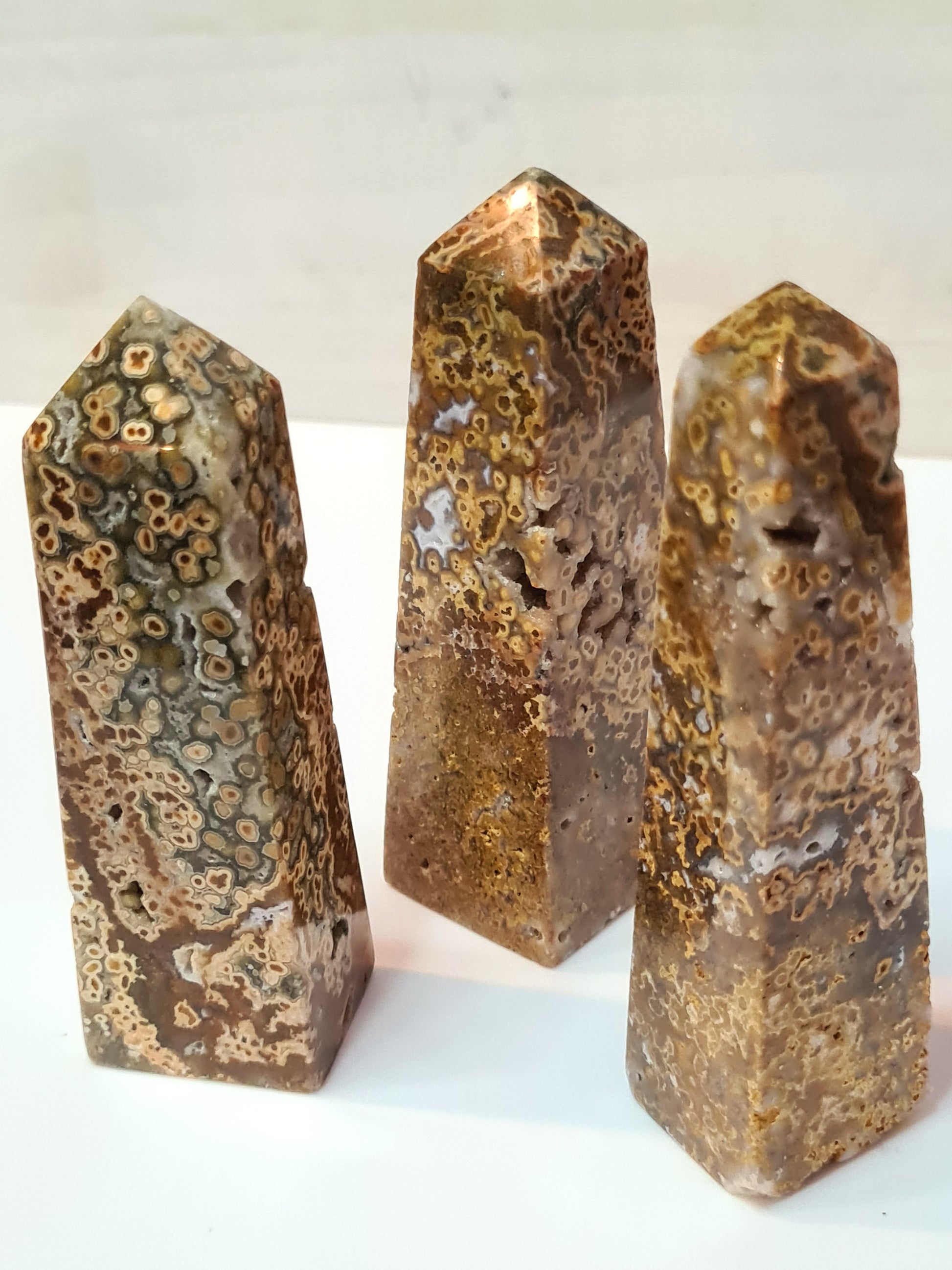 A collection of orbicular jasper obelisks in colours of yellow, mustard, green and white. Each has druzy pockets of quartz.