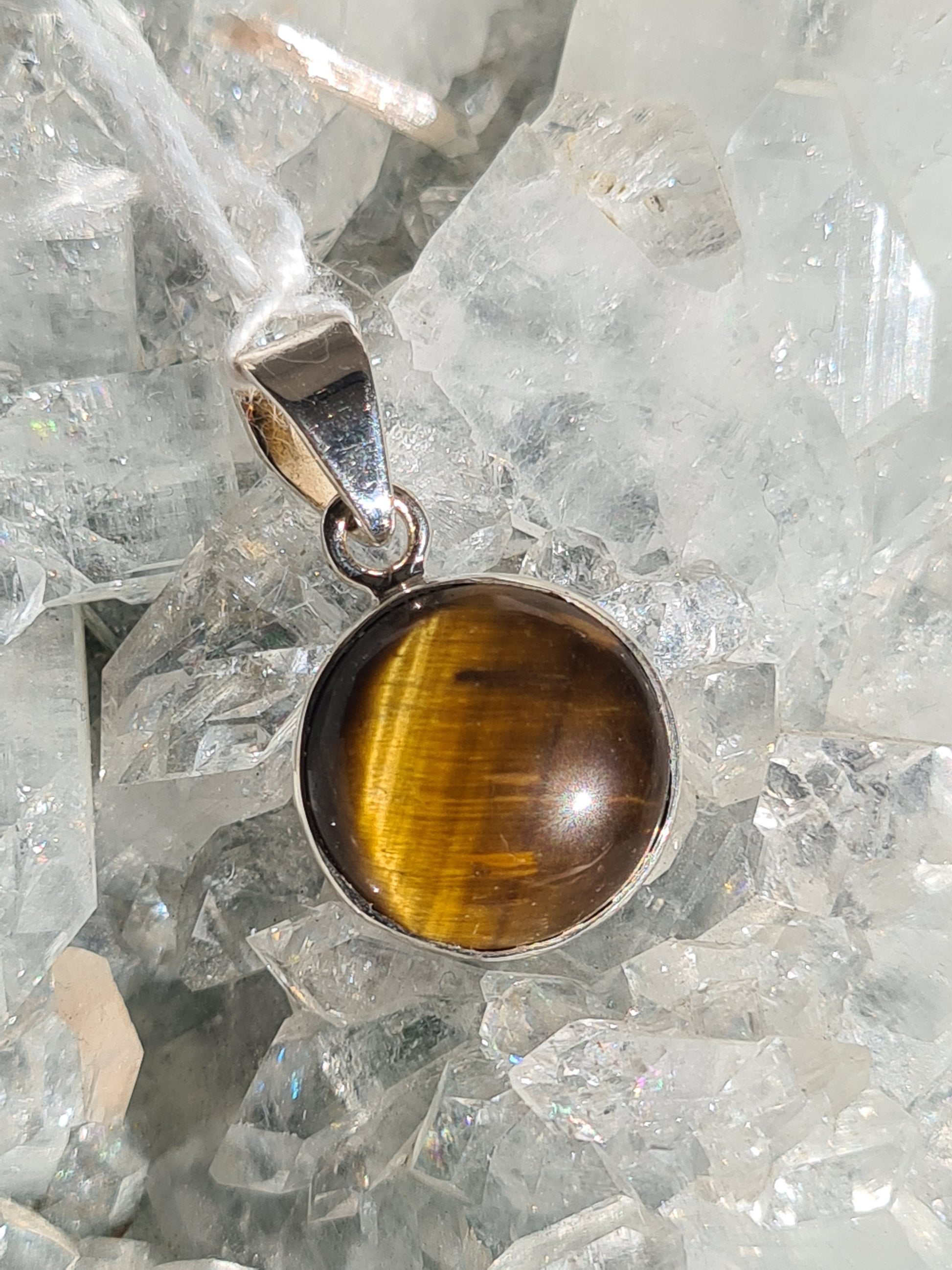 Golden Tigers Eye Pendant. A round cabochon, rubover set in Sterling Silver. 
Photographed on an apophyllite cluster background. 