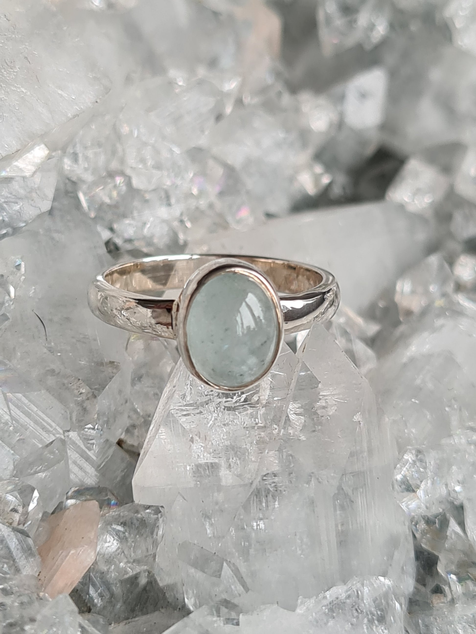 A rubover set Brazilian aquamarine cabochon, oval shaped, set into sterling silver with a solid D-shaped polished band. UK Size N
