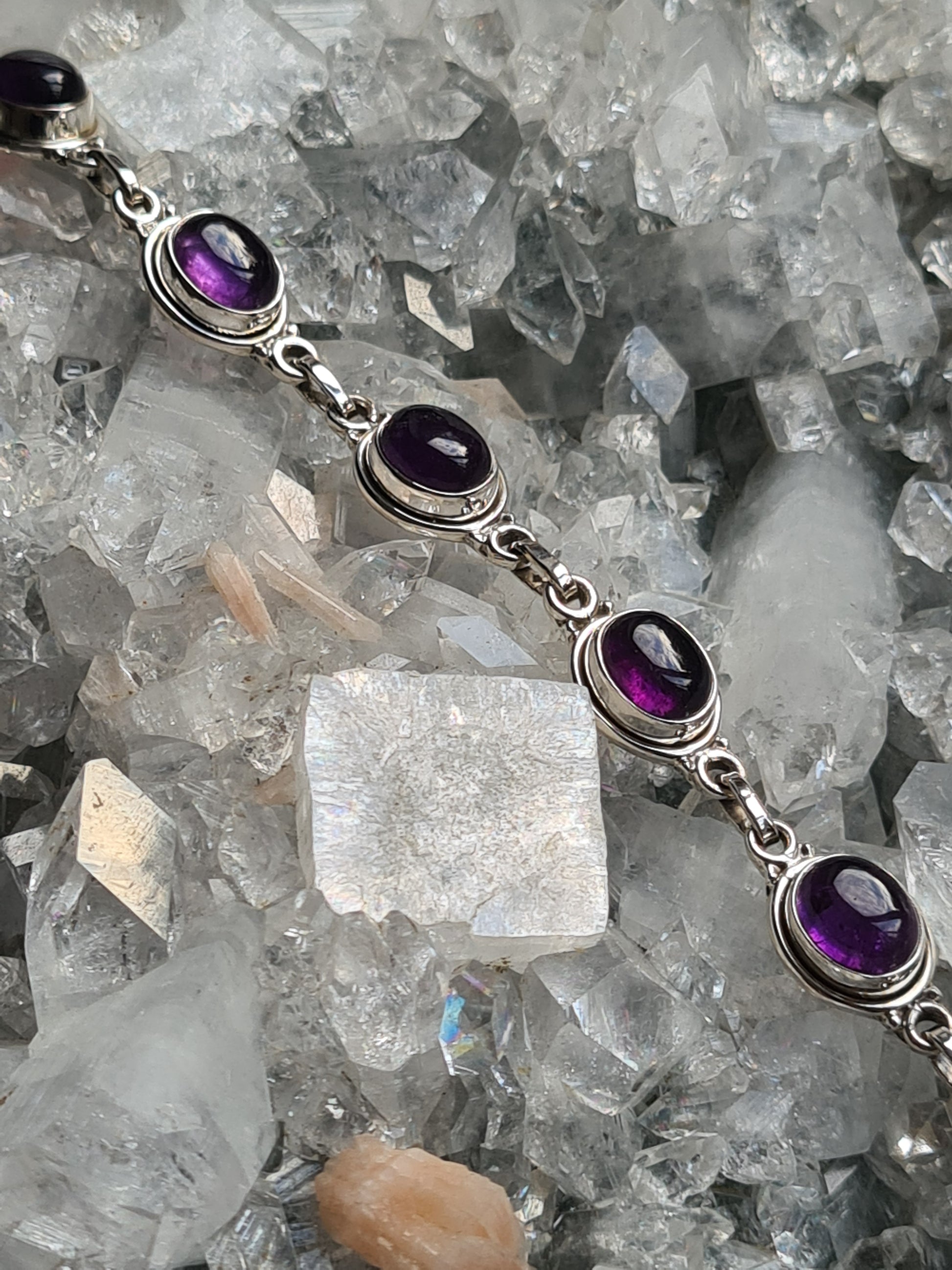 A Sterling Silver Bracelet, rubover set with oval cabochon amethyst gemstones (7 in total). Lobster clasp. Measures from 19cm to 20.8cm in length
