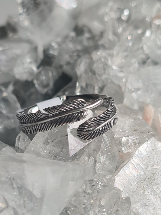 An adjustable cross over feather ring in sterling silver. Size UK P.5