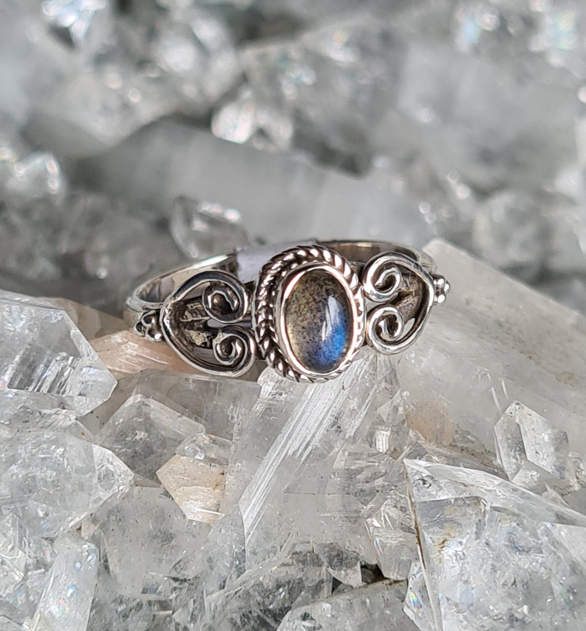 Vintage style labradorite ring, centres on a rubover oval cabochon with blue flash, twisted rope border and heart shaped wire shoulders. UK Size O