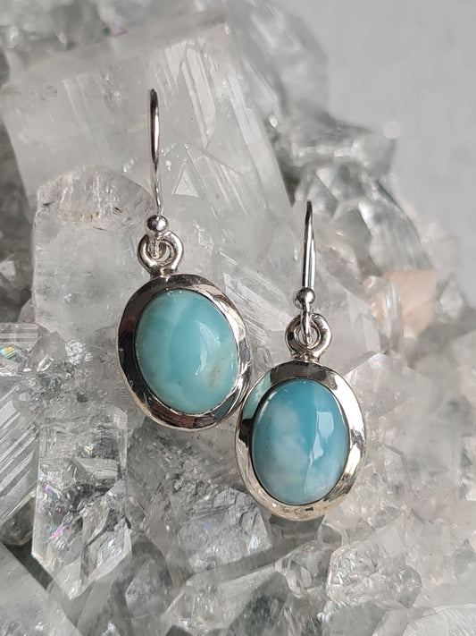 A pair of Blue Larimar Drop earrings in sterling silver. Oval shaped in rubover frame.