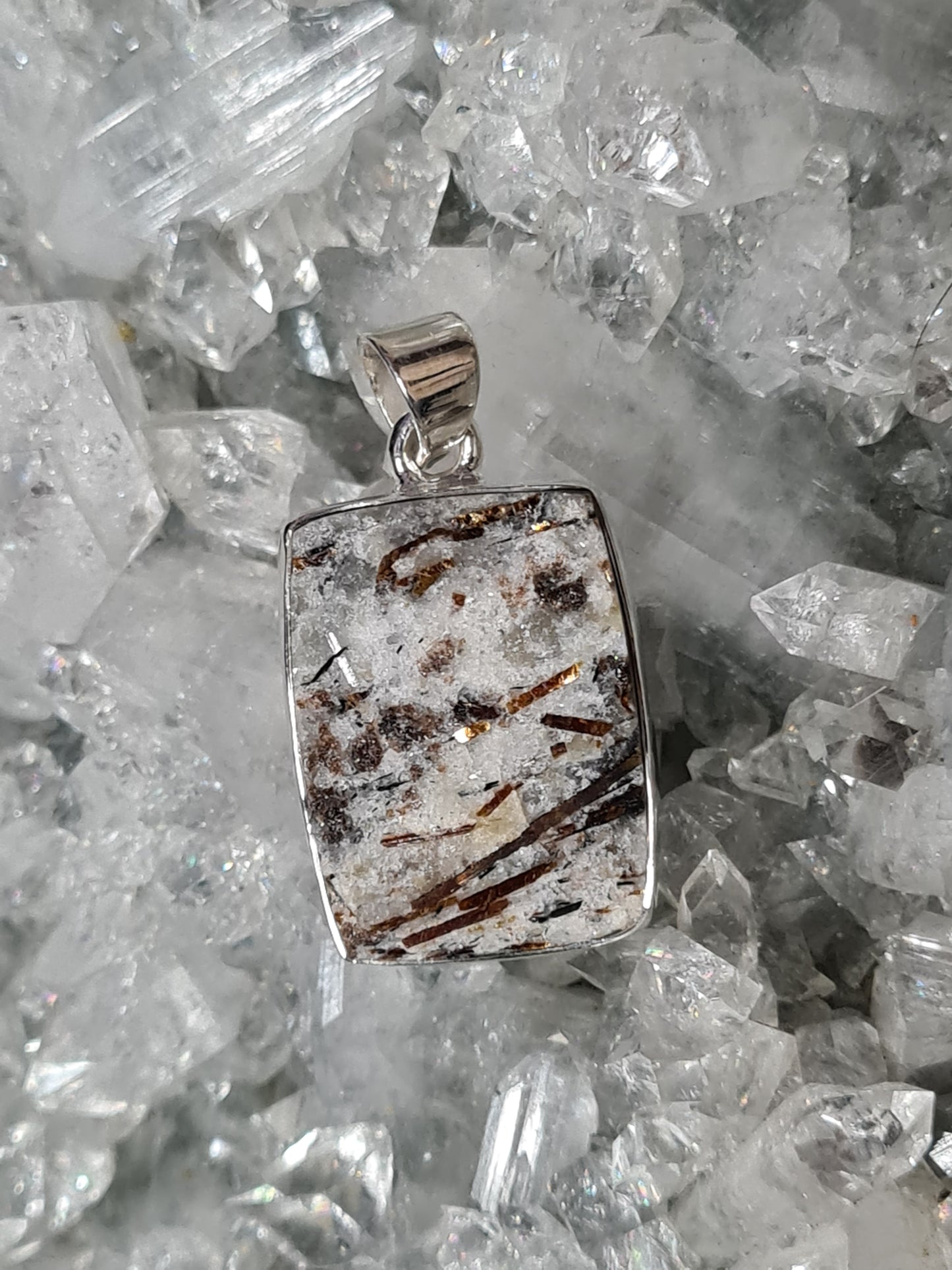 A rectangular cut raw astrophyllite pendant in sterling silver. 35mm in length