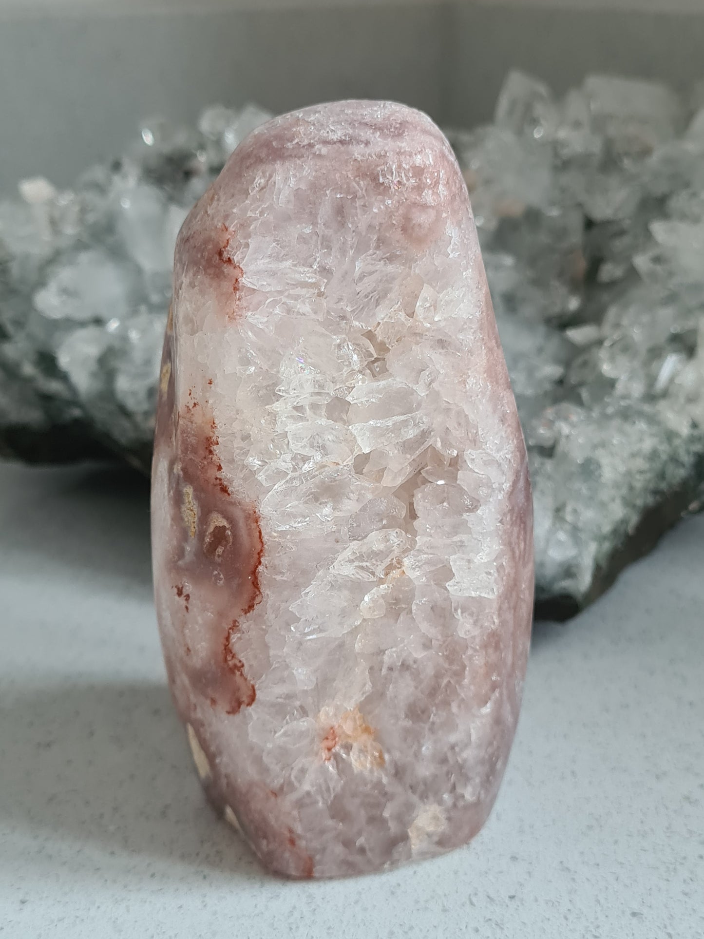 Natural Pink Amethyst Polished Raw Freefrom. Pink colour with large clear quartz cluster centre. Photographed with apophyllite cluster in the background.