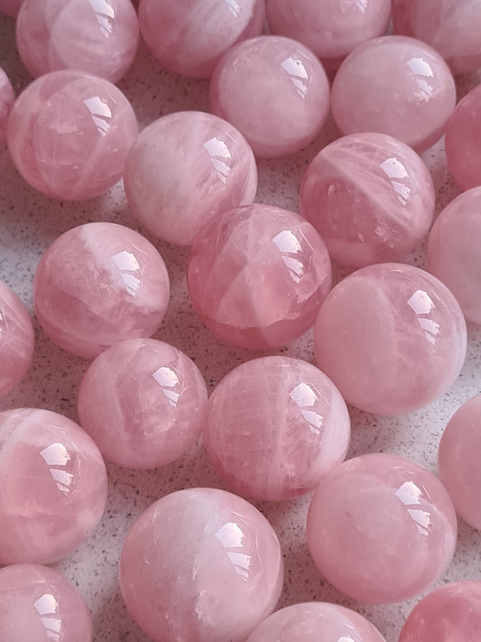 Collection of Rose Quartz Small Spheres from India. Natural banding seen in the pink crystals 